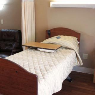 A hospital bed in a healthcare setting with a side table attached.