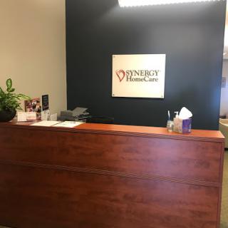 A reception area of a medical office featuring a wooden desk and healthcare signage.