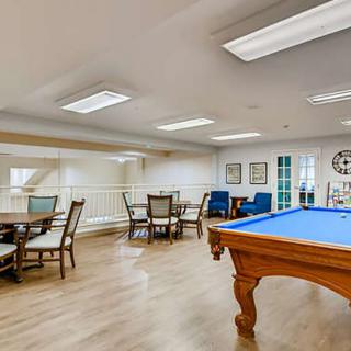 A well-lit game room featuring a billiards table and seating area.