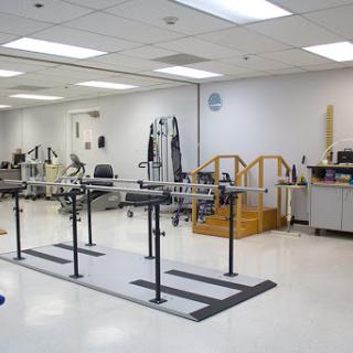 A physical therapy room equipped with parallel bars and various exercise machines for rehabilitation.