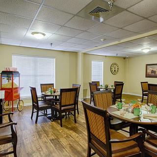 A cozy dining area with several tables and chairs, featuring a popcorn machine and wooden flooring.