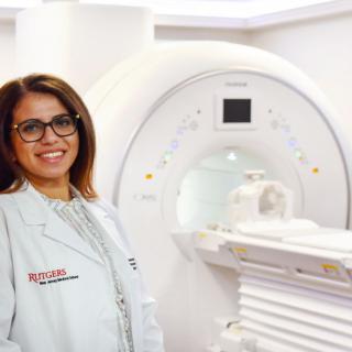 A medical professional standing next to an MRI machine in a hospital setting.