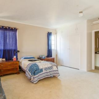 A cozy bedroom with a single bed and blue curtains letting in natural light.