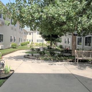A peaceful courtyard with benches and trees, surrounded by residential buildings.
