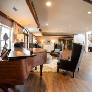 A cozy living room with a grand piano and stylish armchairs on a wooden floor.