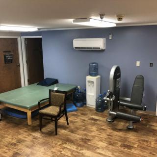 A physical therapy room with exercise equipment and a treatment table.