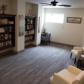 A cozy library room with bookshelves, armchairs, and a reading nook by the window.