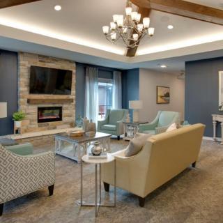 A modern living room with elegant furnishings, featuring a fireplace and a chandelier.