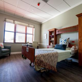 A well-lit hospital room with a single bed and comfortable furnishings.