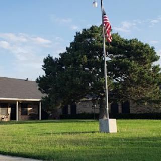 A suburban building with an American flag on a flagpole and a neatly maintained lawn.
