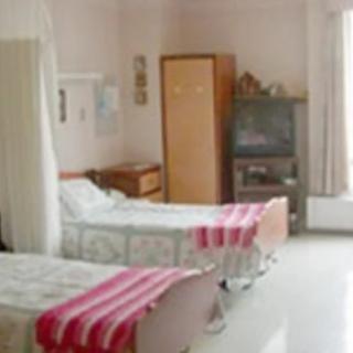 A hospital room with two beds, a wardrobe, and a television.