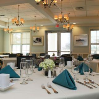 An elegantly set dining table in a restaurant, complete with folded napkins, glassware, and floral centerpieces.