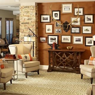 A cozy living room featuring two armchairs, a console table adorned with decorative items, and a gallery wall of framed art.