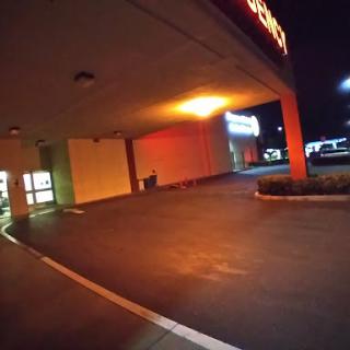 An illuminated storefront and empty parking lot captured at night.