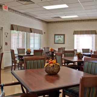 A well-lit dining area with neatly arranged tables and chairs, decorated with autumn-themed centerpieces.