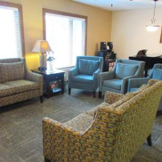 A cozy living room with a sofa, chairs, and a piano.