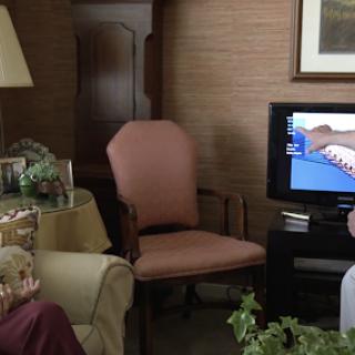 A cozy living room setup featuring a sofa, an armchair, a table lamp, and a television.