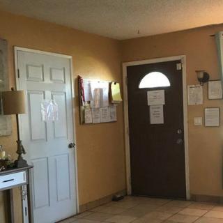 A cozy hallway with a door, decorated wall, and a lamp on the side table.