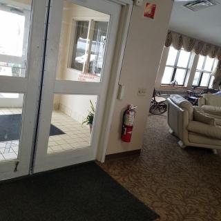 A cozy lobby area with large windows and comfortable seating near a set of glass doors.