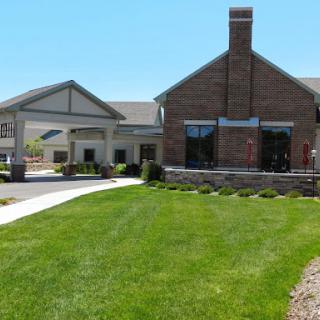 A well-maintained residential building with a manicured lawn and clear blue skies.