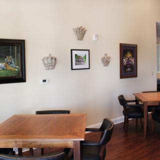 A cozy cafe interior featuring wooden tables, black chairs, and framed artwork on the walls.