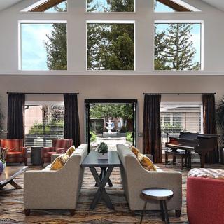 A spacious living room with high ceilings, modern furniture, and large windows letting in natural light.