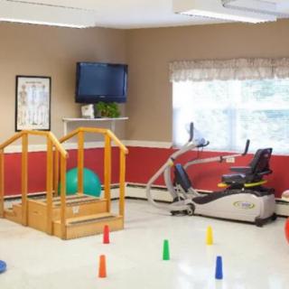 A physical therapy room equipped with exercise machines and colorful cones.