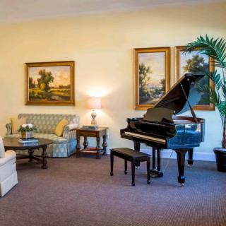 A cozy living room featuring a grand piano and elegant artwork on the walls.