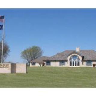 A large house with a well-maintained lawn and two flags flying in the foreground.