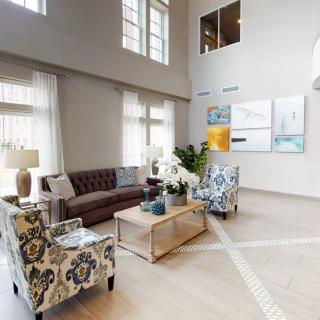 A spacious living room with elegant decor, featuring a leather sofa, patterned armchairs, and modern artwork on the walls.