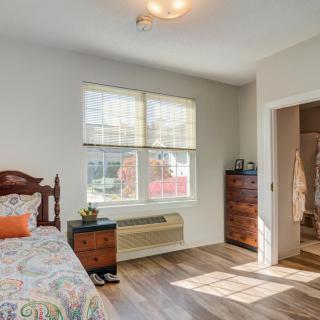 A cozy bedroom with a wooden bed and ample natural light streaming through the windows.