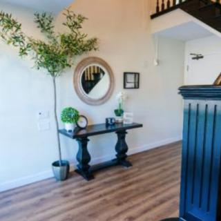 A stylish entryway featuring a console table with decorative items, a round mirror, and a potted plant on wooden flooring.