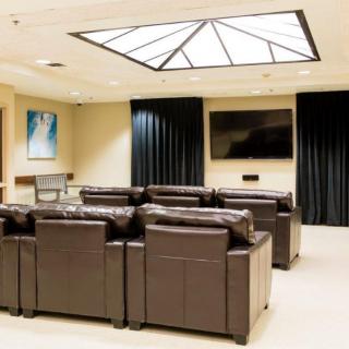 A modern home theater setup with leather couches and a large TV under a skylight.