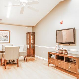 A cozy living room with a dining area, featuring a television, a wooden cabinet, and stylish furnishings.