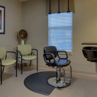 A cozy beauty salon waiting area with a hairdressing station and chairs.