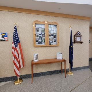 An interior view showcasing the U.S. flag and a state flag, accompanied by a photo display mounted on the wall.