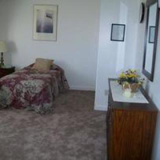 A cozy bedroom with a single bed, floral bedspread, and simple decor.