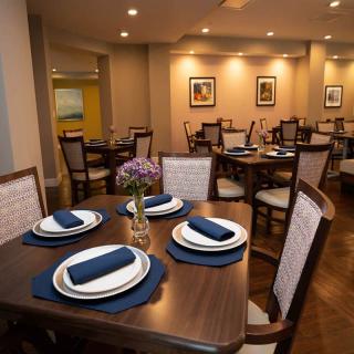 An elegantly set dining area with neatly arranged tables and chairs, featuring blue napkins and centerpieces.
