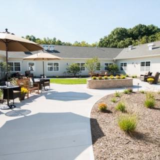 A sunny courtyard with outdoor seating, tables, and a landscaped garden area.