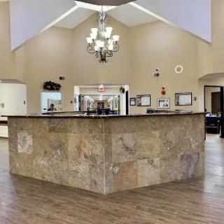 A spacious and well-lit lobby featuring a stone reception desk and elegant chandelier.