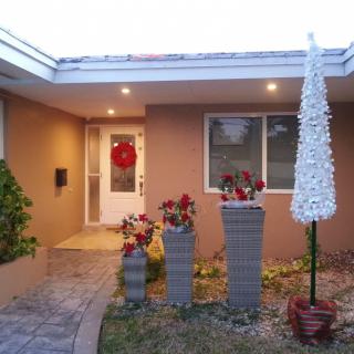 A festive house entrance with holiday decorations and potted plants.