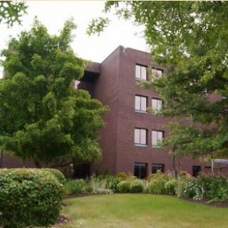 A modern brick building surrounded by lush greenery.