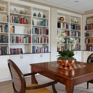 A cozy home library with wooden furniture and shelves filled with books.