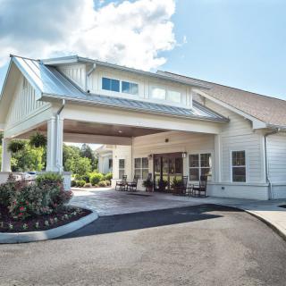 A modern building with a covered entrance and landscaped driveway.