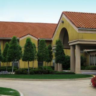 A large building with a tiled roof and landscaped entrance.