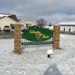 A sign for a real estate property stands amidst a snowy landscape.