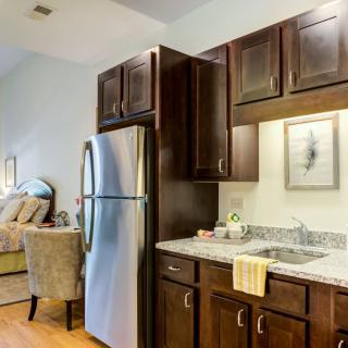 A modern kitchen with stainless steel appliances and granite countertops, opening into a cozy living area.