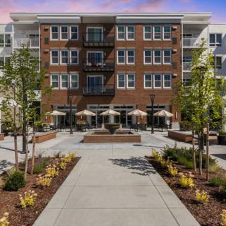 A modern apartment building with landscaped pathways and outdoor seating areas.
