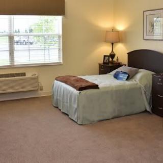 A cozy bedroom with a single bed, nightstand, and window providing natural light.