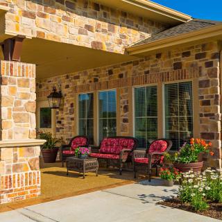A cozy outdoor patio with comfortable seating against a brick house.